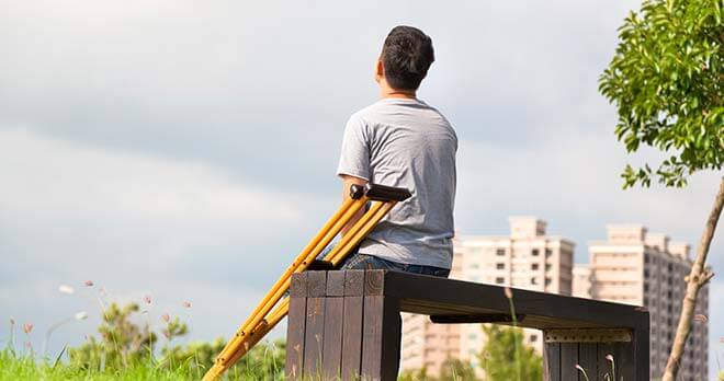 man sitting on bench with crutches